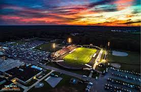 An aerial photograph of the Community Football Stadium in Bedford, Michigan taken at night before the sun is fully set. Bedford, Michigan is a location served by AAA Standard Services.